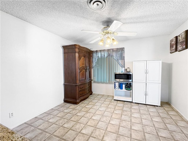 kitchen featuring stainless steel microwave, a textured ceiling, and ceiling fan