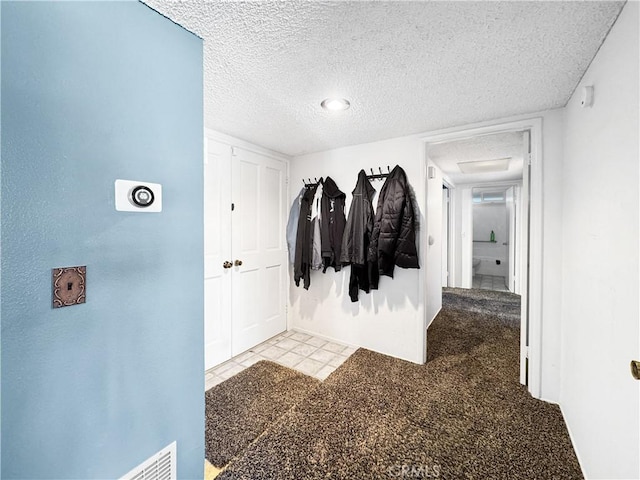 hall with light carpet and a textured ceiling