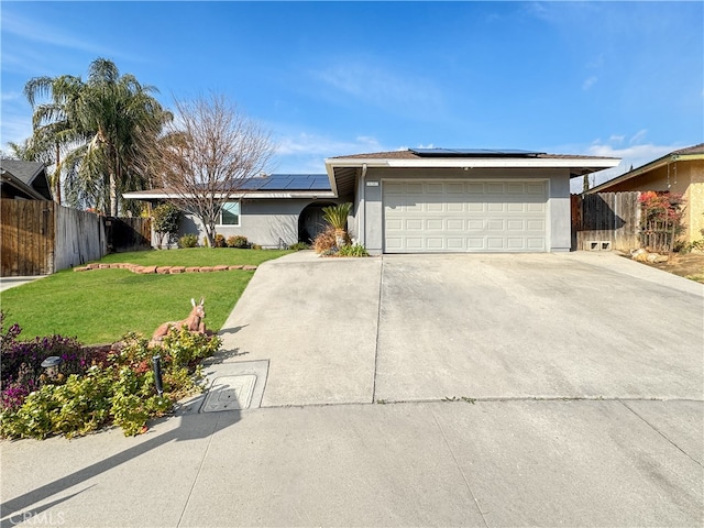 ranch-style home with a garage, a front yard, and solar panels