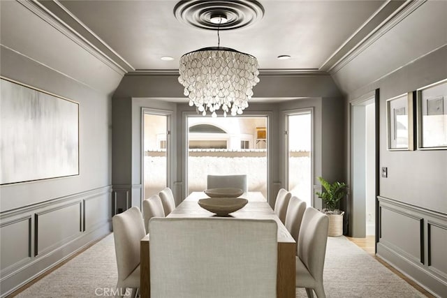 dining room with ornamental molding, vaulted ceiling, an inviting chandelier, and light hardwood / wood-style flooring