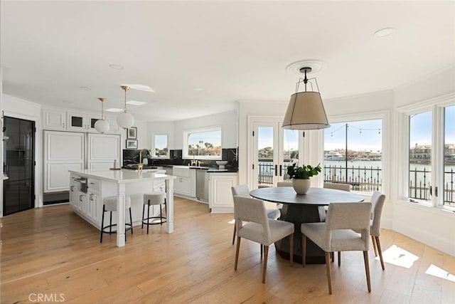 dining area featuring a water view, light hardwood / wood-style flooring, and a wealth of natural light