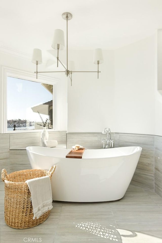 bathroom featuring tile walls, tile patterned floors, and a tub to relax in