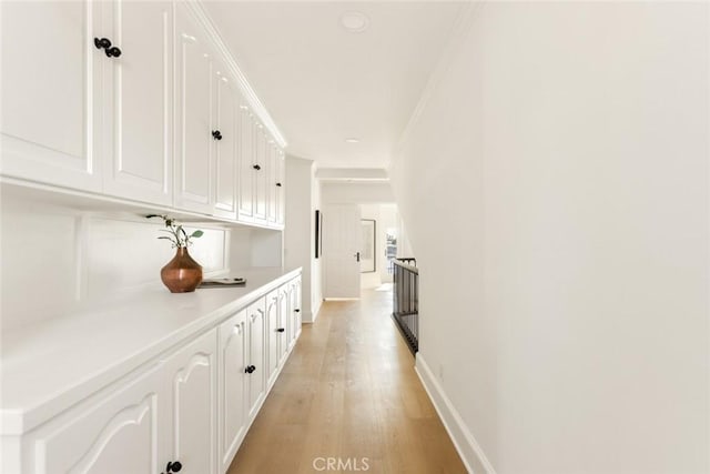 corridor featuring ornamental molding and light hardwood / wood-style floors