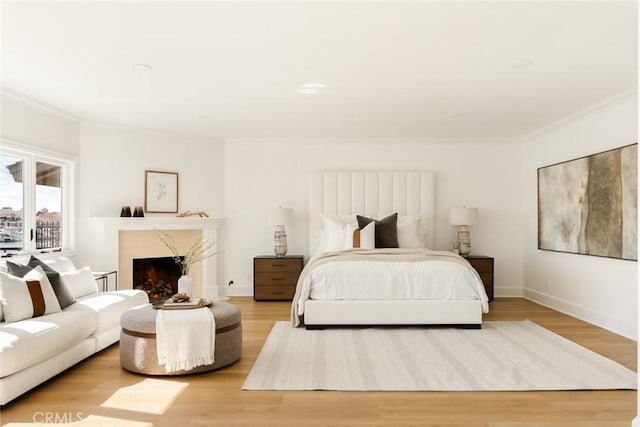 bedroom featuring hardwood / wood-style flooring, ornamental molding, and a premium fireplace