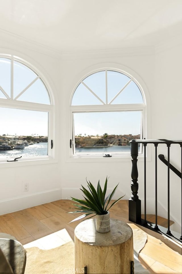 sitting room featuring hardwood / wood-style flooring, crown molding, and a water view