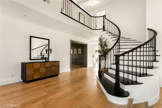 stairs featuring a towering ceiling and wood-type flooring