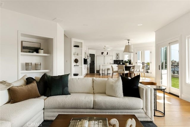 living room featuring sink, built in shelves, and light hardwood / wood-style flooring