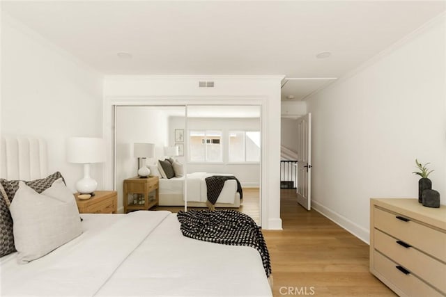 bedroom featuring crown molding, light hardwood / wood-style flooring, and a closet