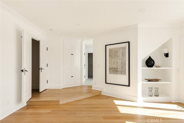 hall featuring hardwood / wood-style flooring, crown molding, and built in shelves