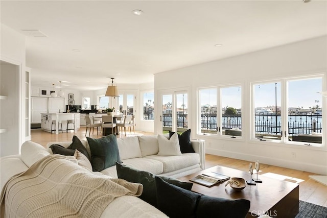 living room featuring a water view, plenty of natural light, and light hardwood / wood-style floors