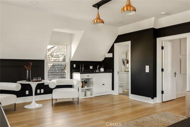 sitting room featuring lofted ceiling, sink, and light wood-type flooring