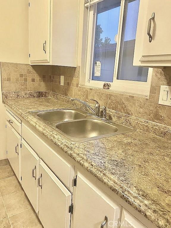 kitchen with light tile patterned flooring, sink, decorative backsplash, and white cabinets