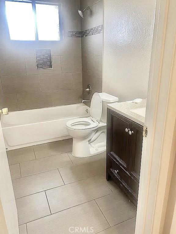 full bathroom with tiled shower / bath combo, vanity, tile patterned floors, and toilet