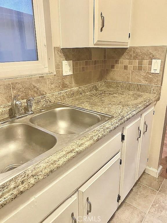 kitchen featuring white cabinetry, sink, tasteful backsplash, and light tile patterned flooring