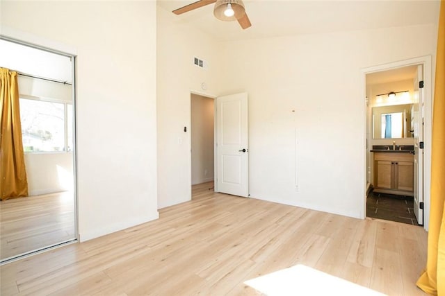 unfurnished bedroom featuring vaulted ceiling, connected bathroom, sink, ceiling fan, and light hardwood / wood-style floors