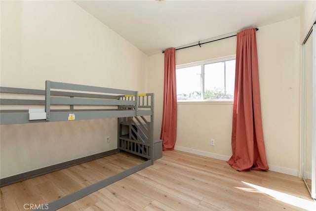 unfurnished bedroom featuring lofted ceiling and light hardwood / wood-style flooring