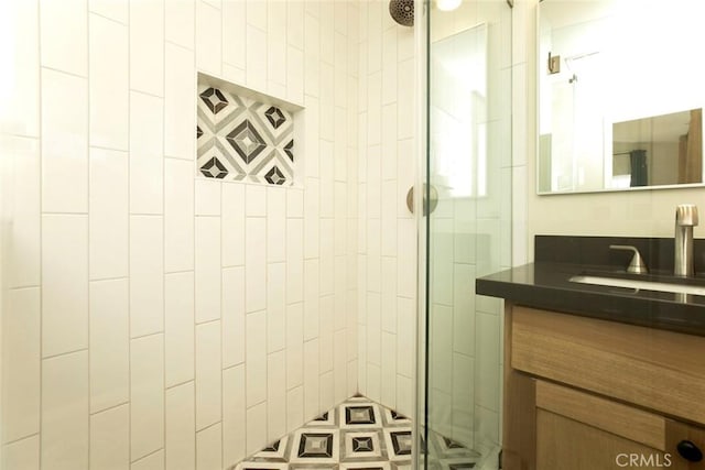 bathroom with tiled shower and vanity