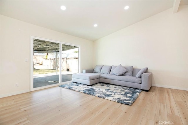 living room featuring lofted ceiling with beams and light hardwood / wood-style flooring