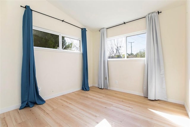 spare room featuring lofted ceiling and light hardwood / wood-style floors