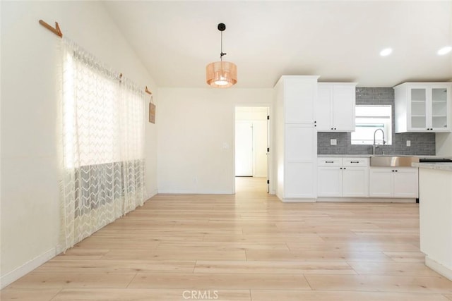 kitchen with pendant lighting, white cabinets, backsplash, and light hardwood / wood-style flooring