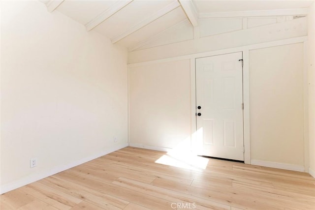 spare room featuring light hardwood / wood-style flooring and vaulted ceiling with beams