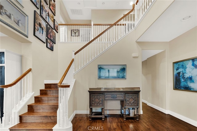 staircase featuring a towering ceiling and hardwood / wood-style floors