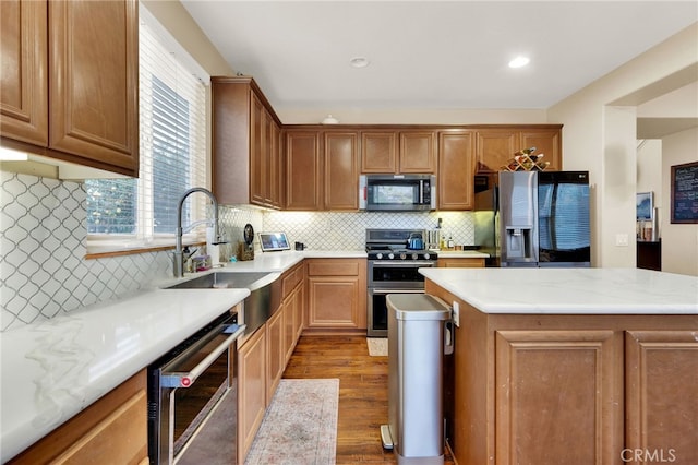 kitchen featuring sink, backsplash, stainless steel appliances, light hardwood / wood-style floors, and a kitchen island