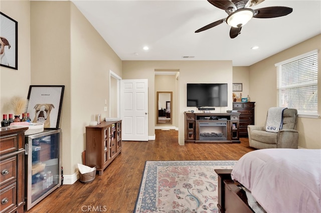 bedroom featuring ceiling fan, dark hardwood / wood-style floors, and a large fireplace