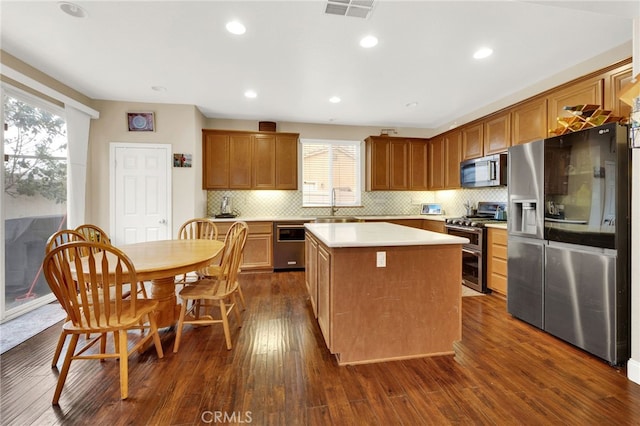 kitchen with a kitchen island, appliances with stainless steel finishes, a wealth of natural light, backsplash, and dark hardwood / wood-style flooring