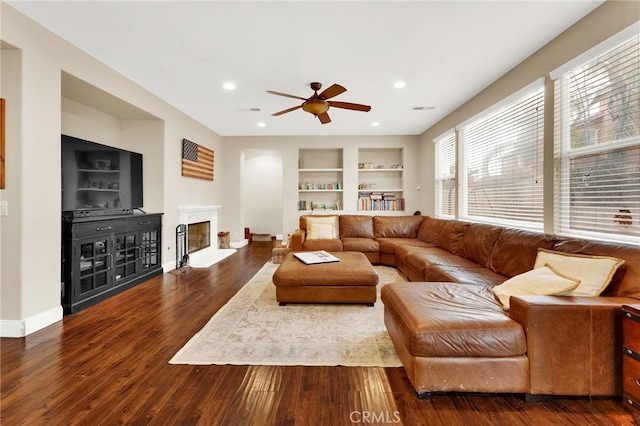 living room with hardwood / wood-style flooring, ceiling fan, and built in shelves