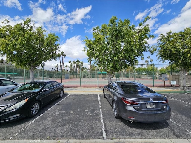 view of car parking featuring tennis court