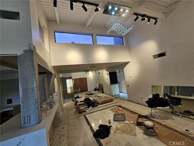 living room featuring wood ceiling, track lighting, beam ceiling, and a high ceiling