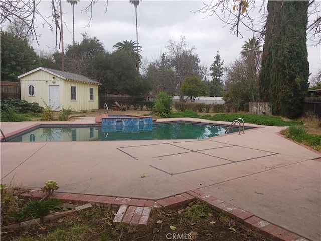 view of swimming pool featuring an outbuilding, a patio, and an in ground hot tub