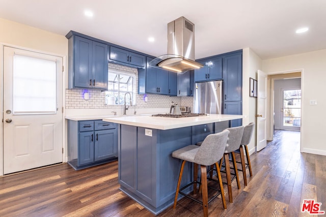 kitchen featuring blue cabinets, island exhaust hood, a center island, and appliances with stainless steel finishes