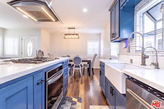 kitchen with pendant lighting, sink, dark wood-type flooring, appliances with stainless steel finishes, and wall chimney exhaust hood