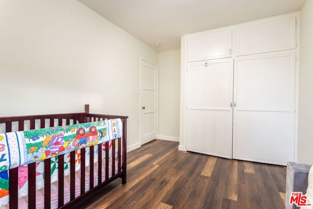 bedroom with a closet, dark hardwood / wood-style floors, and a nursery area