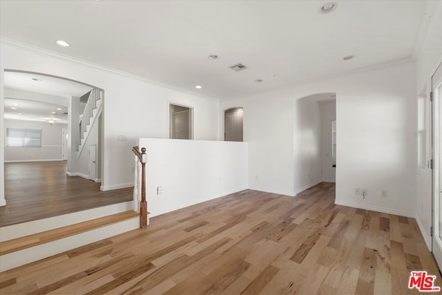 spare room with ornamental molding and light wood-type flooring