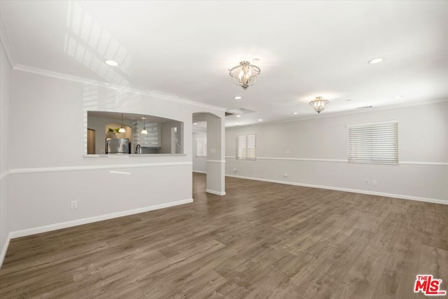 unfurnished living room featuring hardwood / wood-style flooring and crown molding