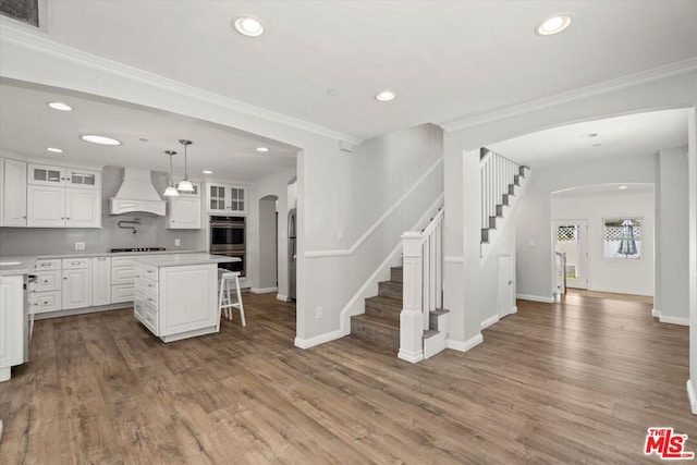 kitchen with premium range hood, a breakfast bar, white cabinetry, a center island, and stainless steel appliances