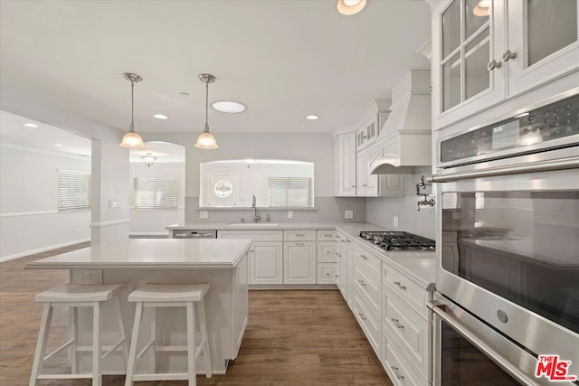 kitchen with premium range hood, sink, a kitchen island, stainless steel appliances, and white cabinets