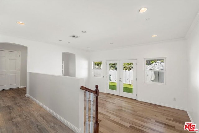 corridor featuring crown molding, light wood-type flooring, and french doors