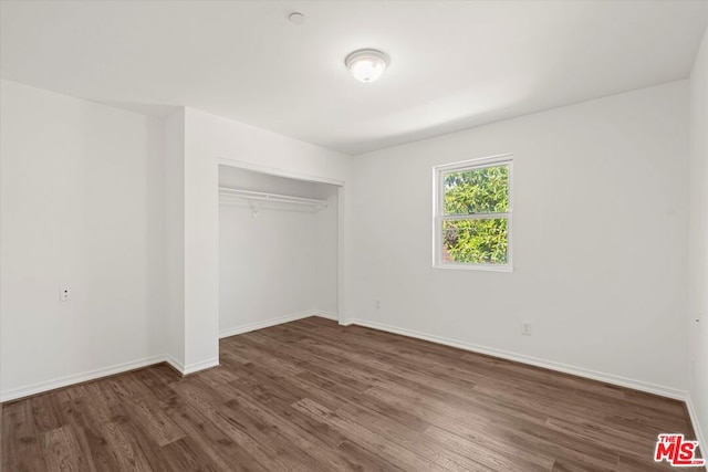 unfurnished bedroom with dark hardwood / wood-style floors and a closet