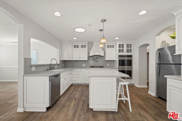 kitchen featuring sink, white cabinetry, a kitchen island, custom range hood, and stainless steel appliances