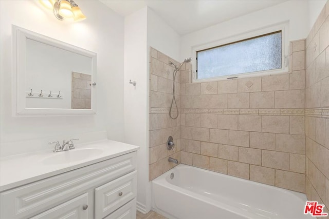 bathroom with tiled shower / bath combo and vanity