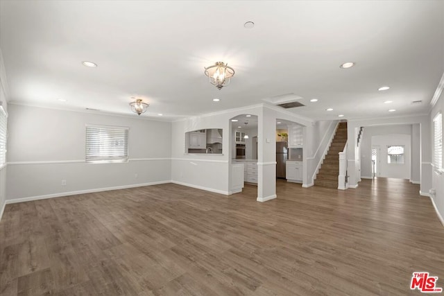 unfurnished living room with ornamental molding and dark hardwood / wood-style floors