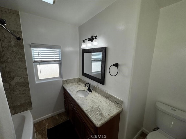 full bathroom featuring tiled shower / bath, vanity, and toilet