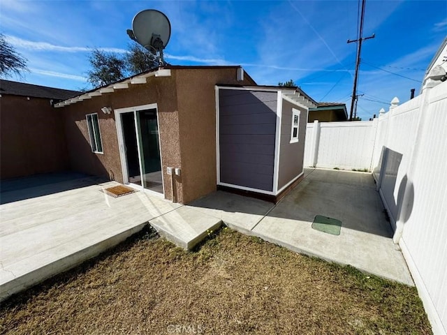 rear view of property featuring a shed and a patio