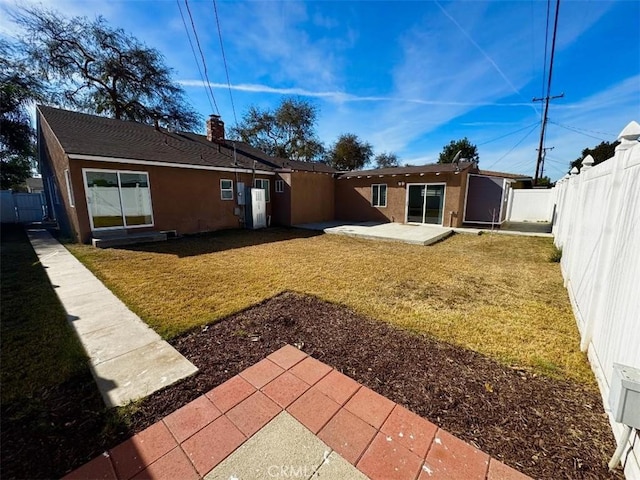 rear view of house featuring a yard and a patio