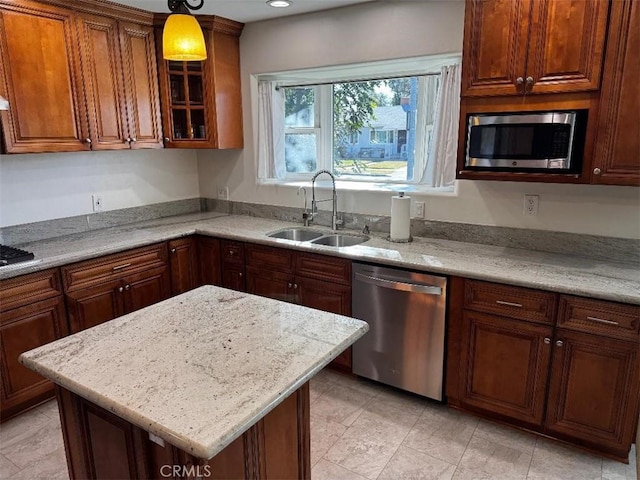 kitchen with sink, hanging light fixtures, stainless steel appliances, light stone countertops, and a kitchen island