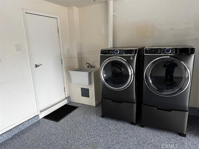 clothes washing area featuring separate washer and dryer and sink